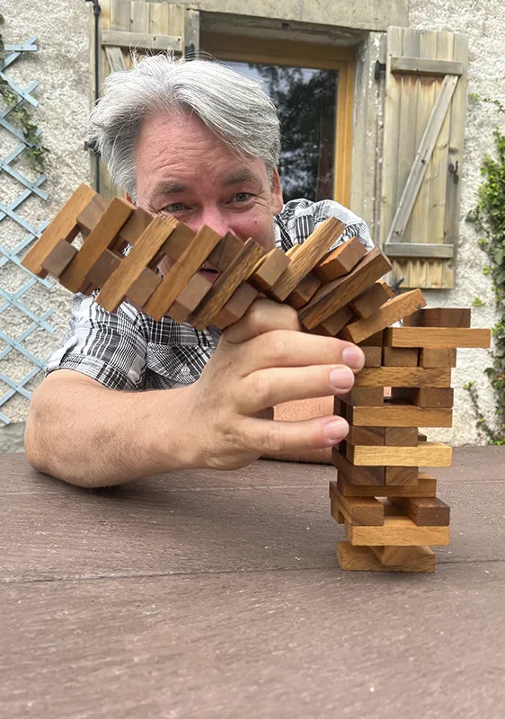 Rainer Weber beim Jenga spielen, der Turm ist am Fallen.